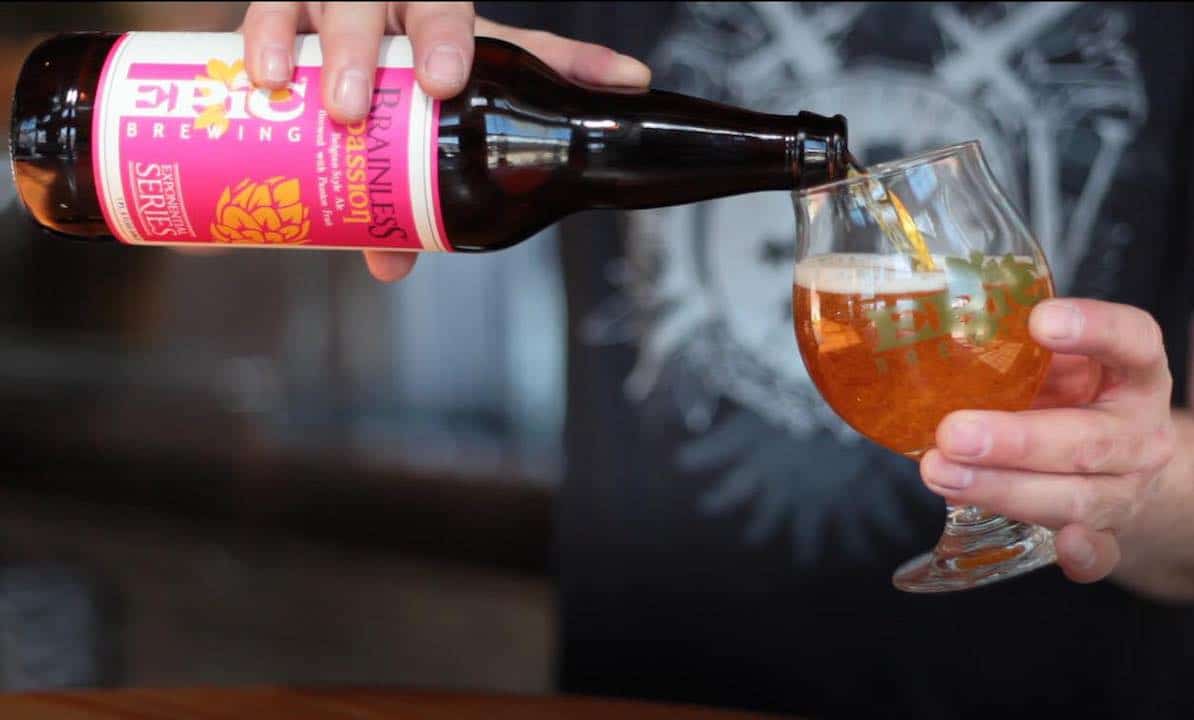 person pouring beer from bottle into glass