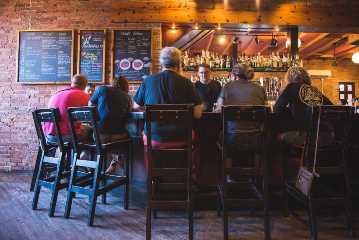 people sitting at a bar and bartender serving them
