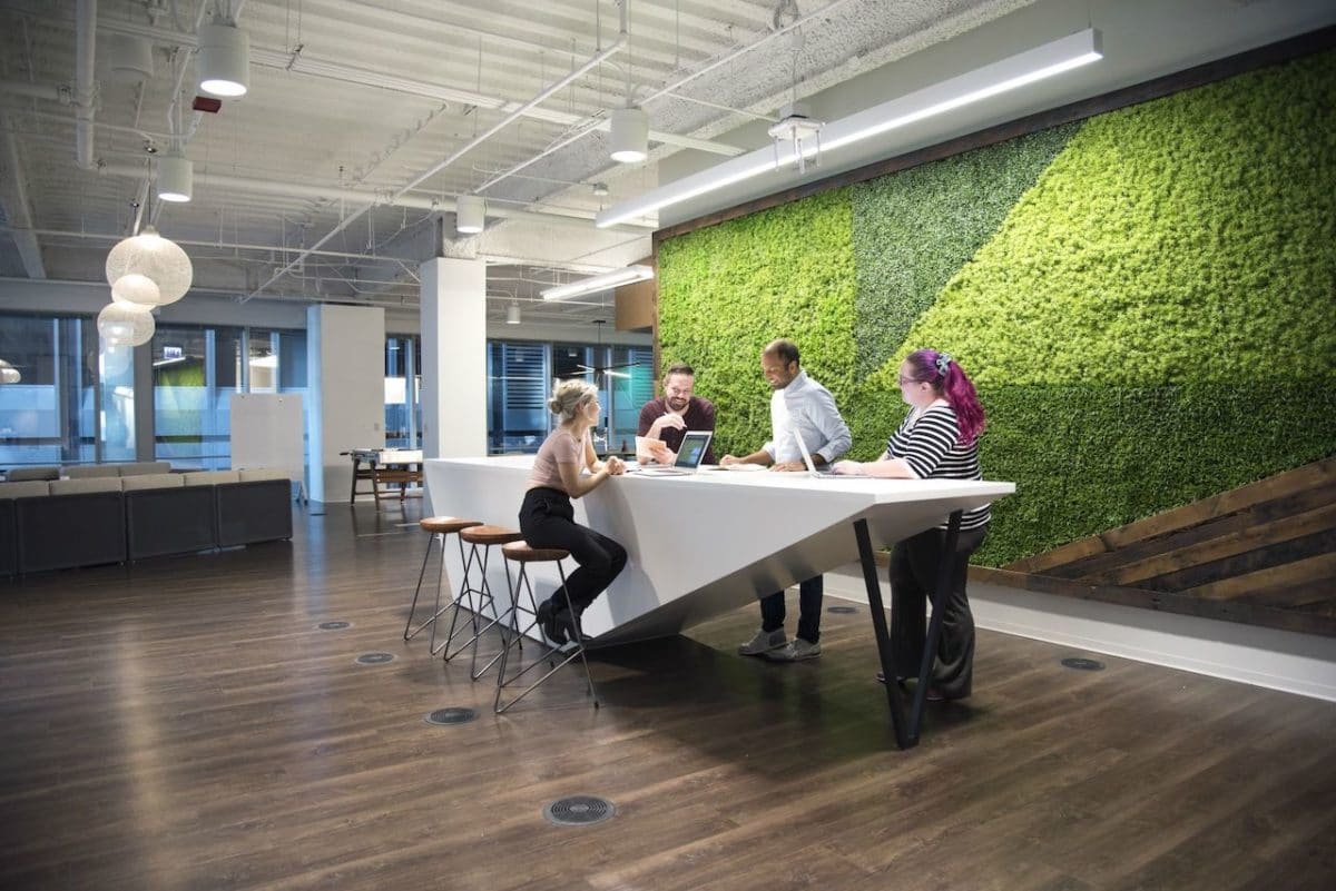 four people in open space office talking over large table