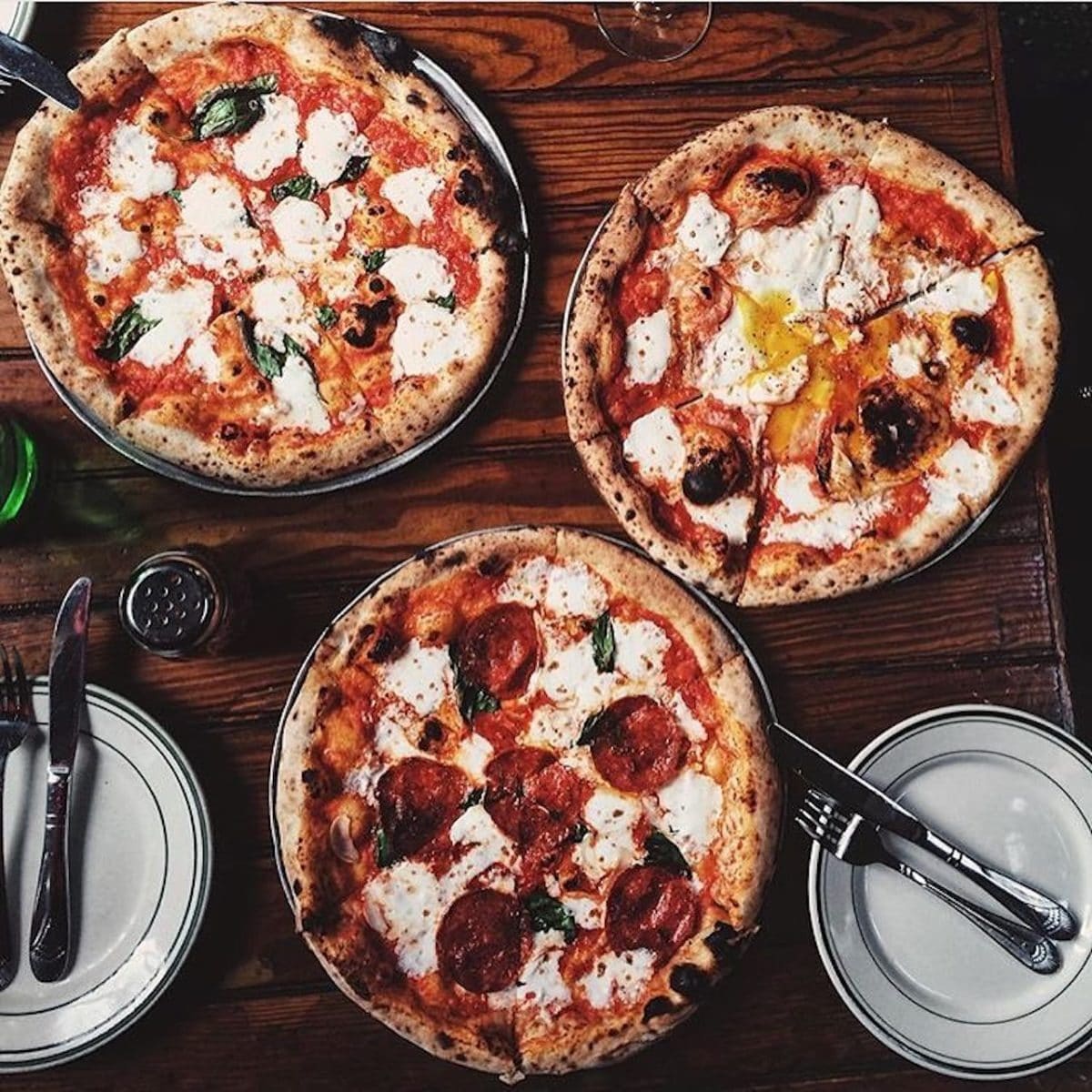 Table full of pizzas, dishes and silverware