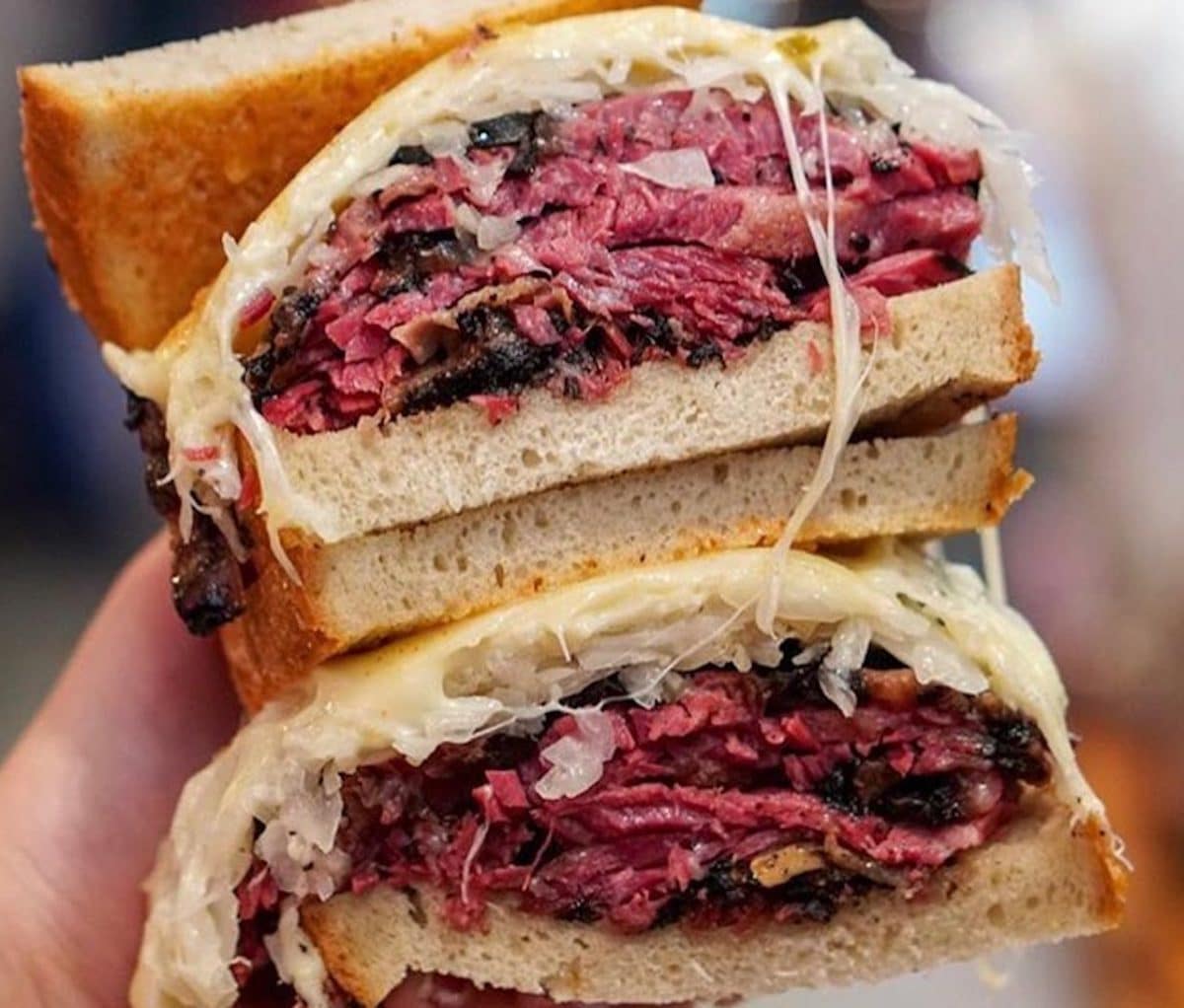 close up of pastrami sandwich with melted cheese