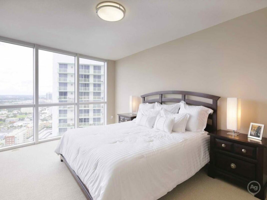 bedroom with be and floor to ceiling windows