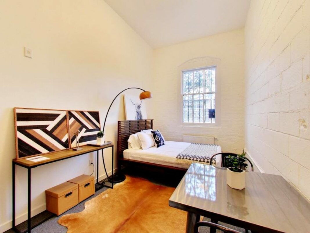 small bedroom with bed and table and tiny window