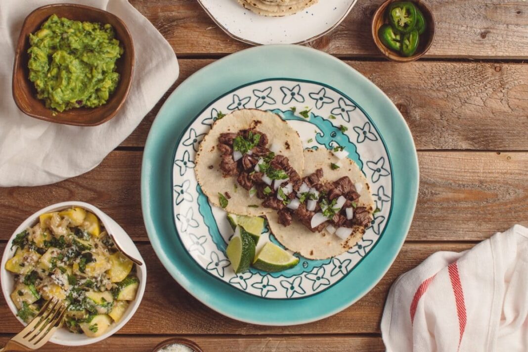 overhead shot of table with tacos, guacamole, and other mexican foods
