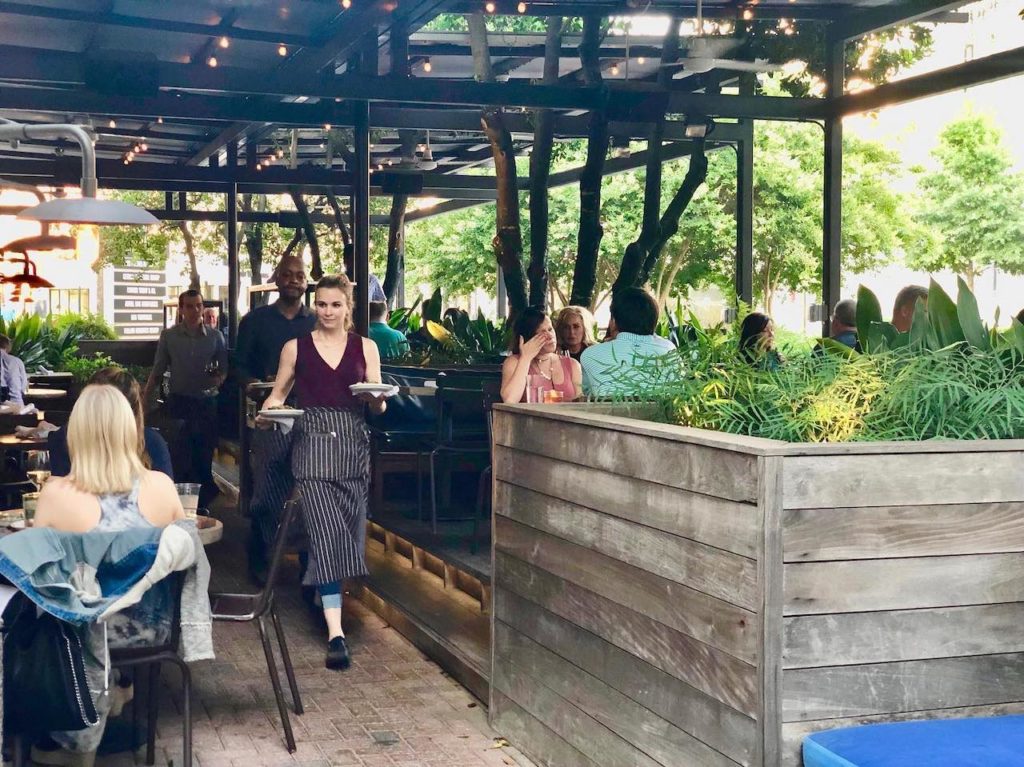 waitress walking on outdoor patio with plates of food