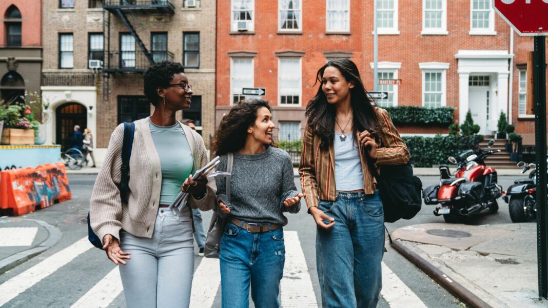 Three friends are walking together in the street - Gay St, New York City, USA